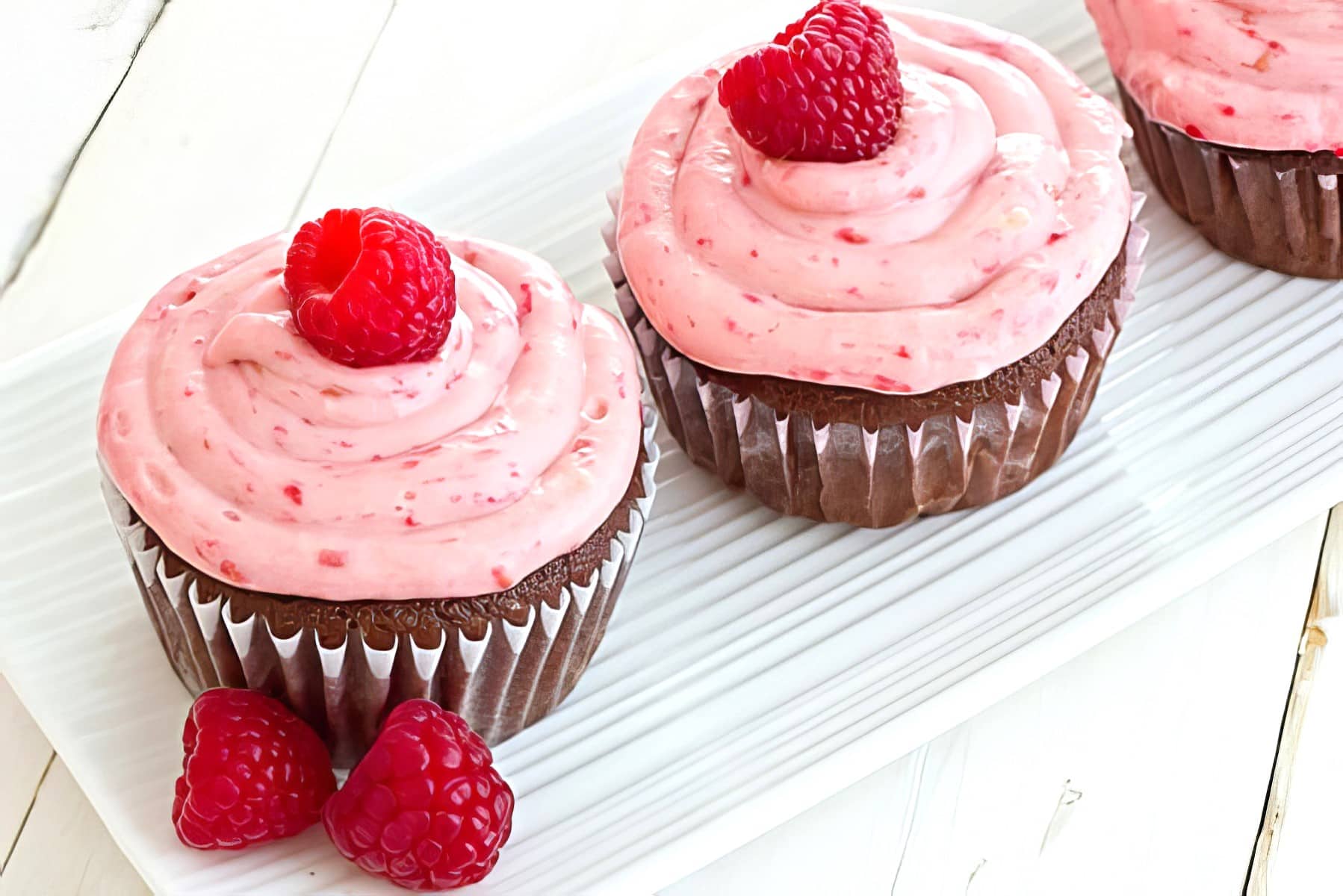 Chocolate Lambic Cupcakes with Raspberry Cream Cheese Frosting being served on a white plate