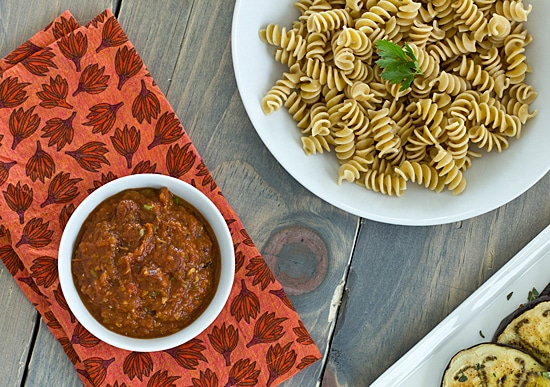 Rotini pasta being served with veggie puttanesca sauce.