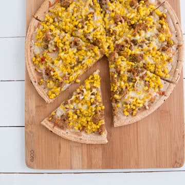 Sweet Corn, Sausage & Thyme Pizza sitting on wooden plate