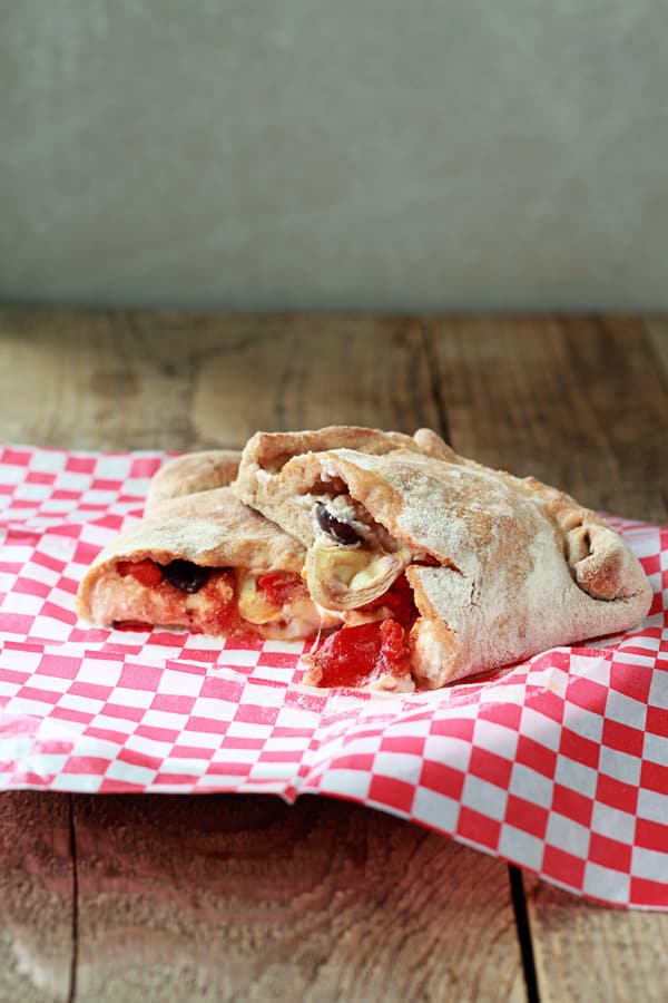 Mediterranean vegetarian Calzones stacked on a red and white checked napkin