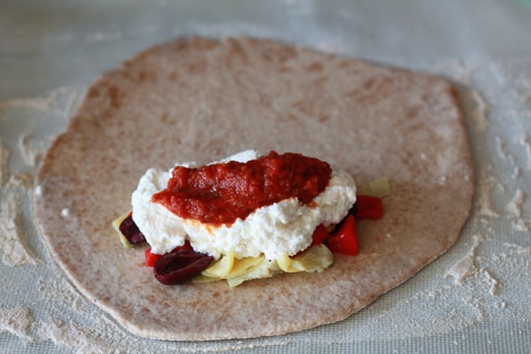 assembling filling inside of mediterranean vegetarian calzone