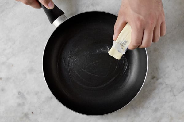 greasing a pan with butter for making crepes