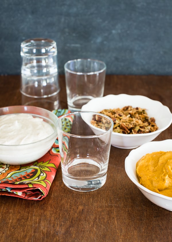 Empty parfait glasses with bowls of cashew coconut cream, spiced pumpkin and crunchy nut topping ready for assembling