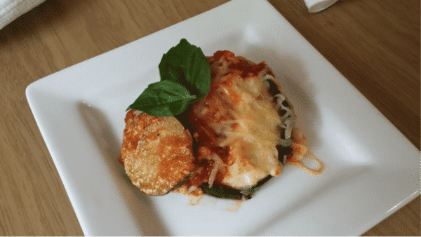 eggplant parmesan on white plate with fresh basil