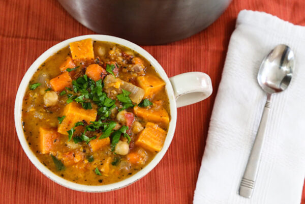 vegan-thanksgiving-sweet-potato-soup-in-mug-on-red-table-cloth-with-silver-spoon