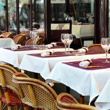 Typical sidewalk restaurant scene in Paris with tables and chairs set for a meal