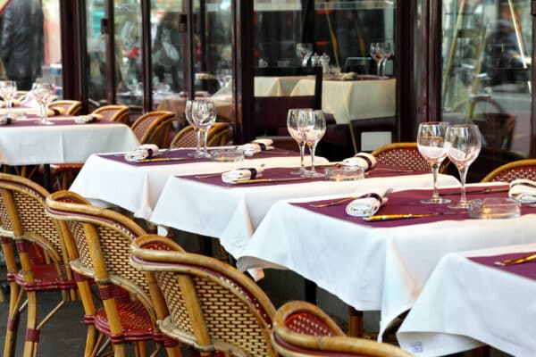 Typical sidewalk restaurant scene in Paris with tables and chairs set for a meal