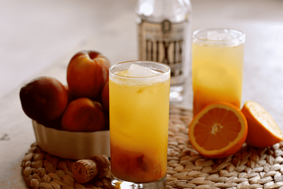 vodka sunrise cocktail with bottle of vodka and fruit