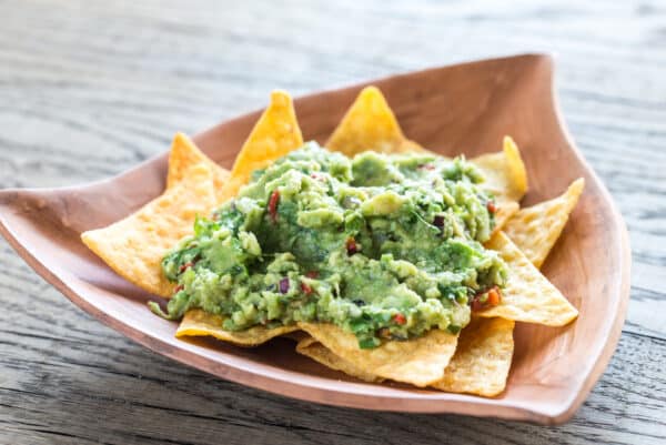 Guacamole with tortilla chips on the wooden background