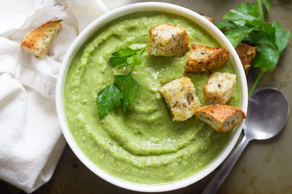 Herbed Fresh Pea Soup with Garlic Croutons being served in a white bowl