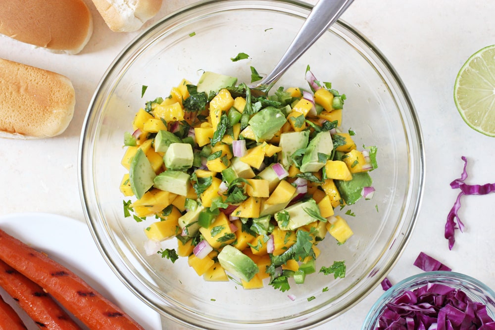 mixing up the mango avocado salsa in a mixing bowl