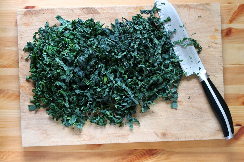 chopping kale on a cutting board to make a kale quiche