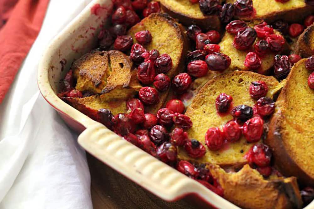Close-up of golden pumpkin French toast casserole with roasted cranberries