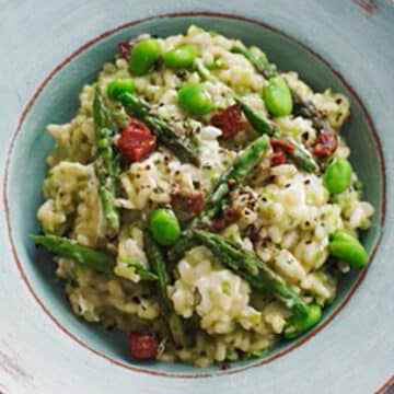 risotto, asparagus, peas, and sun-dried tomatoes in a white bowl