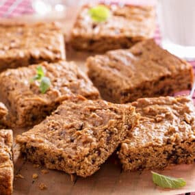 Vegan almond butter blondies sit on a wooden block with sprigs of mint