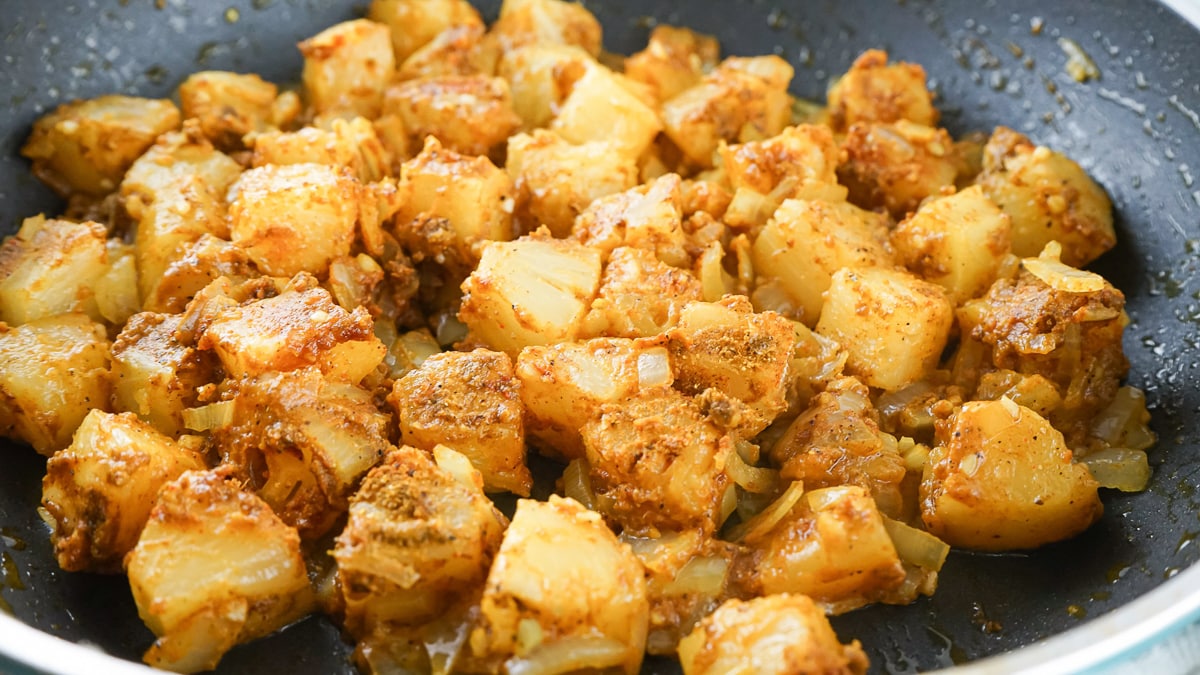 pineapple, onions, garlic, and spices in a frying pan