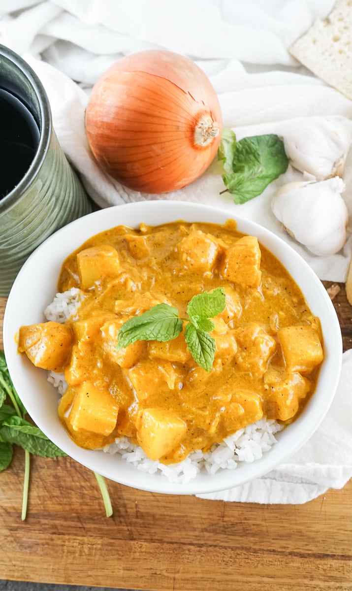 vegetarian pineapple curry in a bowl next to onion