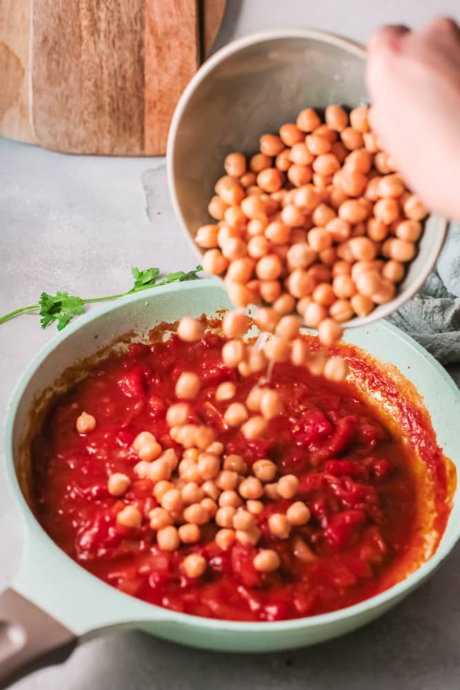 pouring chickpeas into Indian butter curry mixture