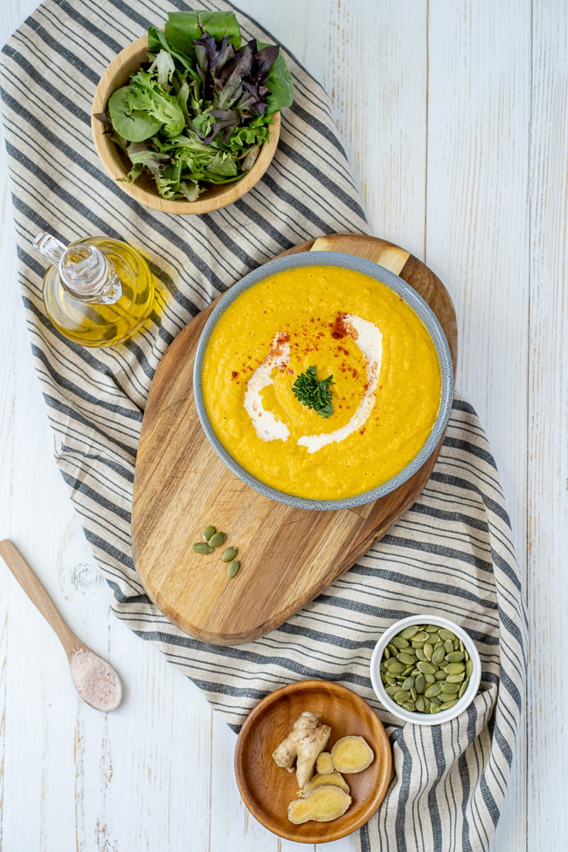 top view of bowl of vegan carrot ginger soup on dish towel