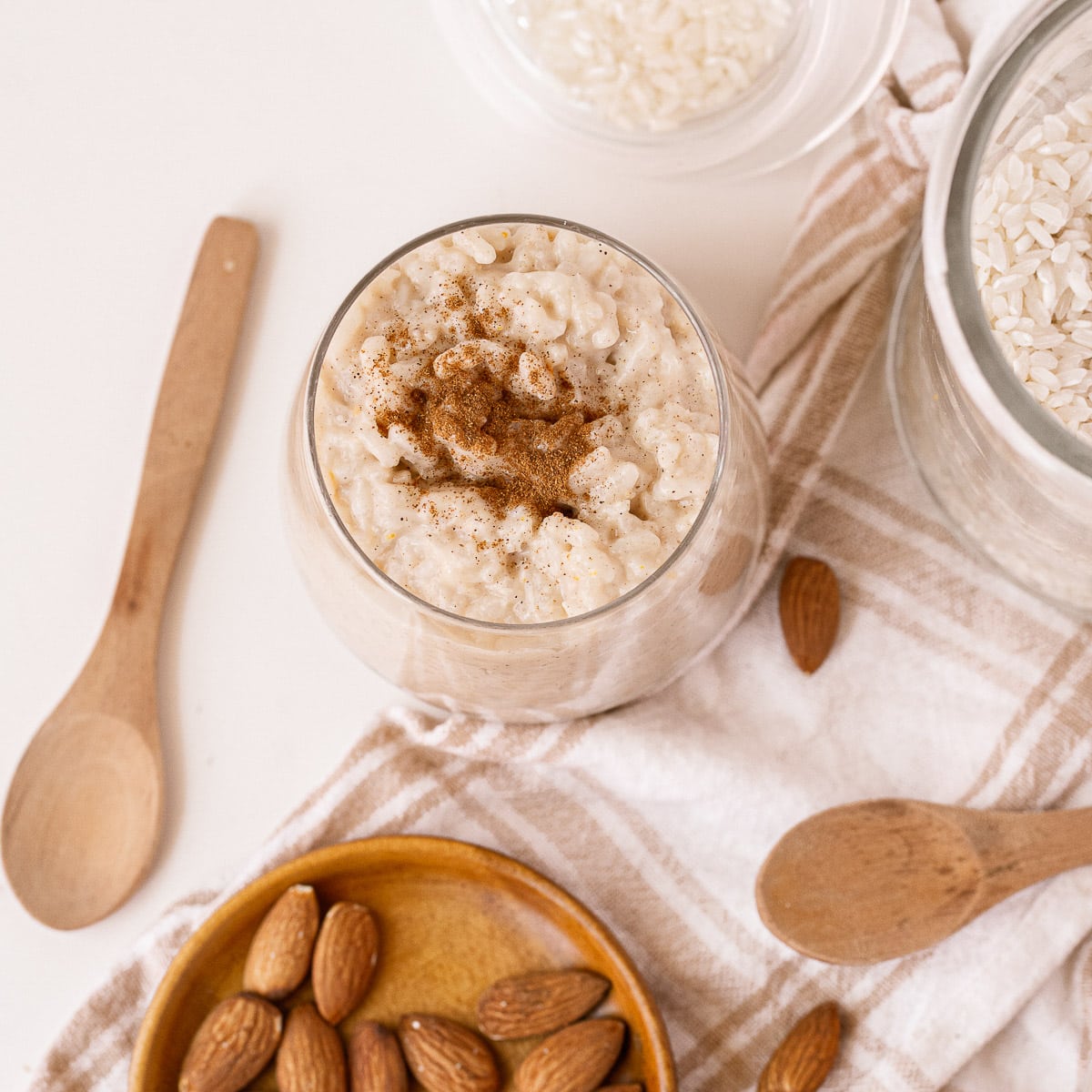 vegan rice pudding being served in a glass with a wooden spoon