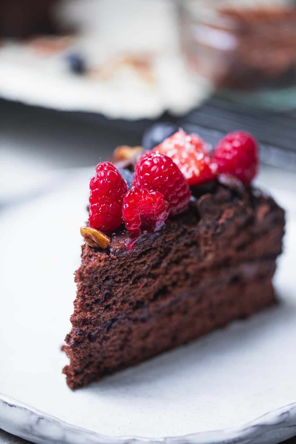 slice of vegan chocolate cake on a white plate with berries