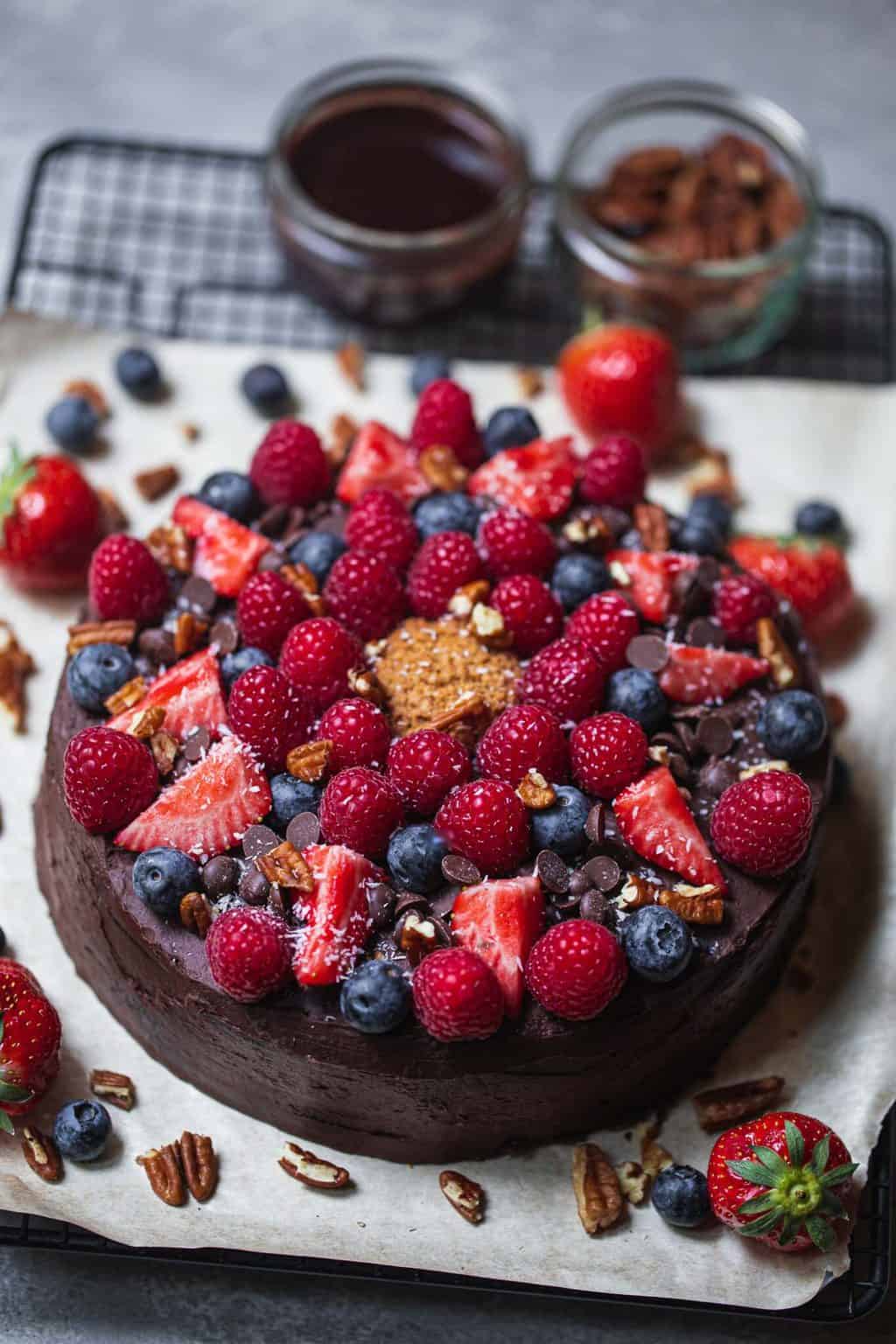 vegan chocolate cake on parchment paper, topped with berries