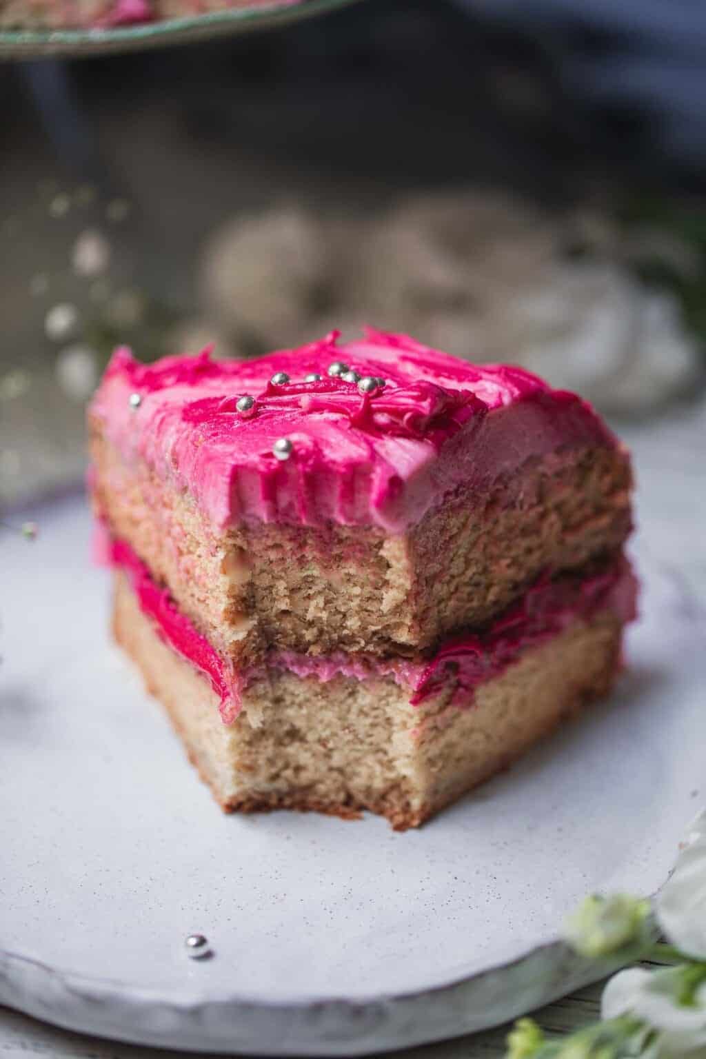 vegan vanilla cake with pink cream cheese frosting on a plate