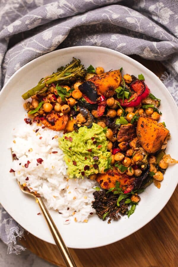 Bowl of roasted chickpeas, sweet potatoes and vegetables with rice and guacamole