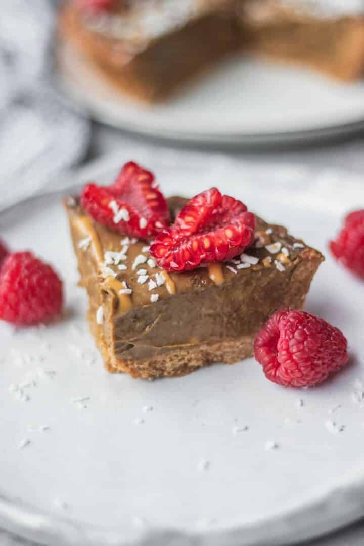 slice of vegan chocolate tart topped with raspberries 