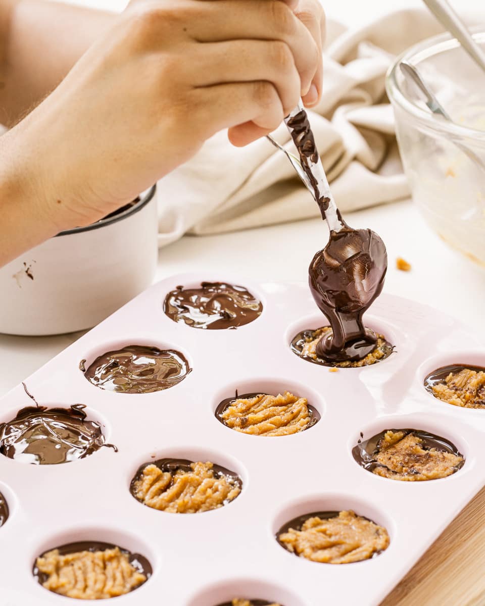 pouring chocolate on top of vegan peanut butter cups