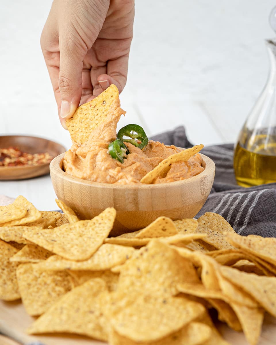 dipping chip into vegan queso