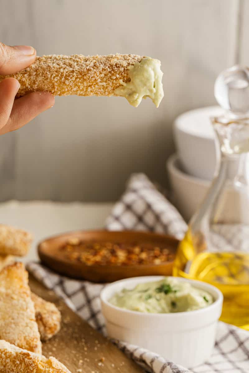 stick of fried halloumi dipped in avocado dip