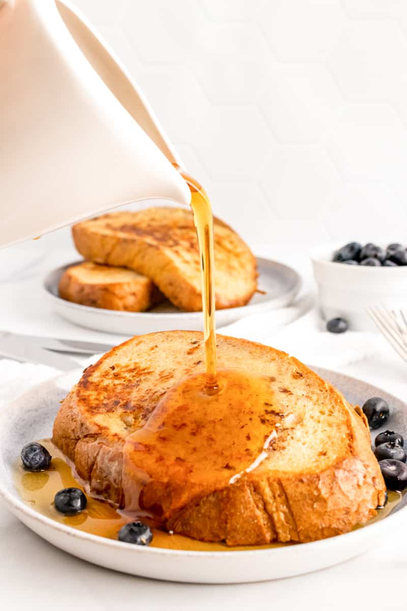 syrup pouring over sourdough French toast on a plate