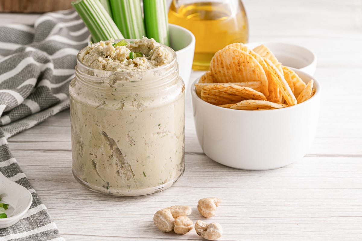 15-minute cashew cheese in a jar next to chips in a small bowl