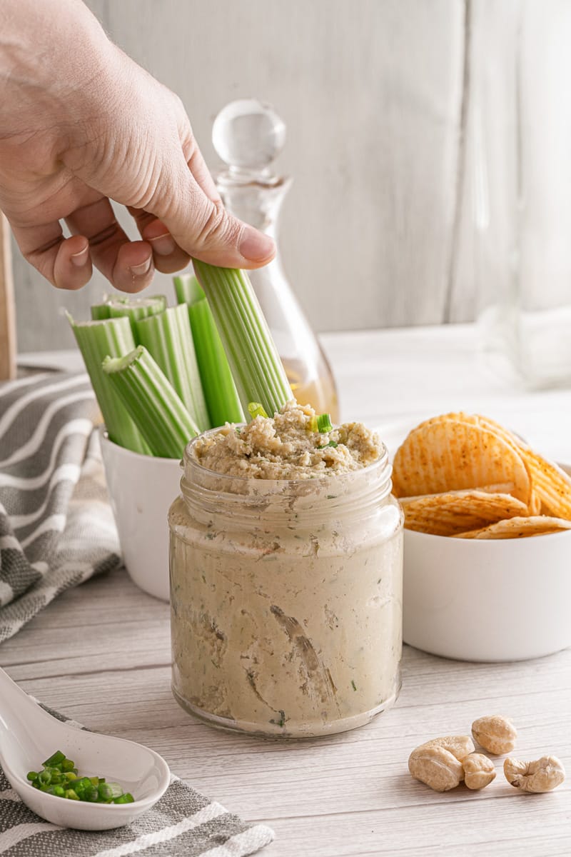 dipping a celery stick into 15-minute cashew cheese