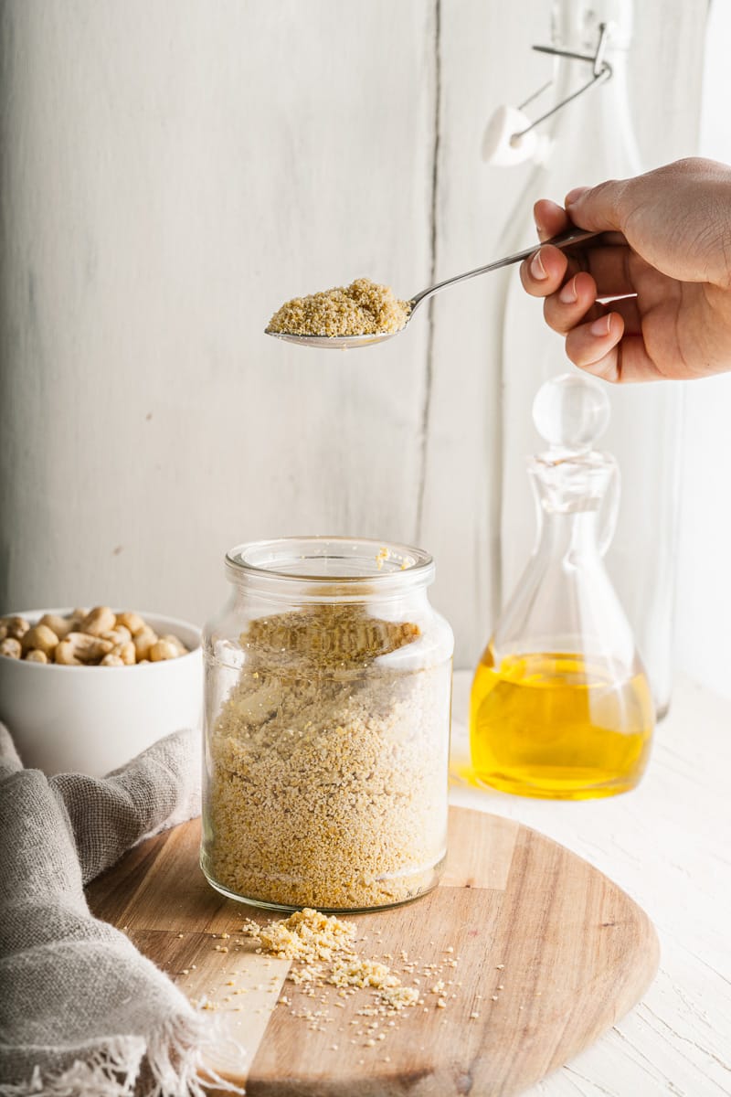 lifting a spoonful of vegan parmesan out of jar