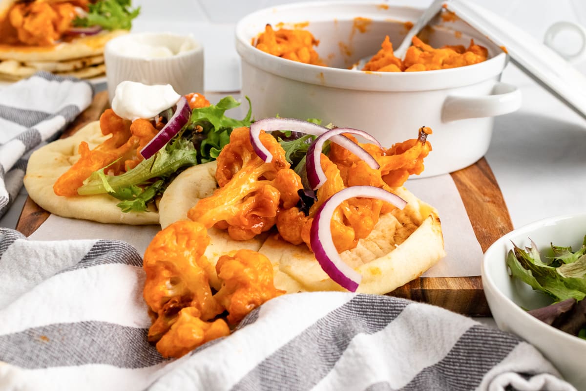 buffalo cauliflower tacos assembles on table with cloths and boards