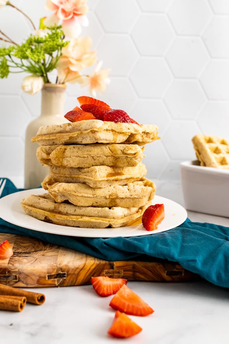 side view stack of vegan waffles on plate with strawberries