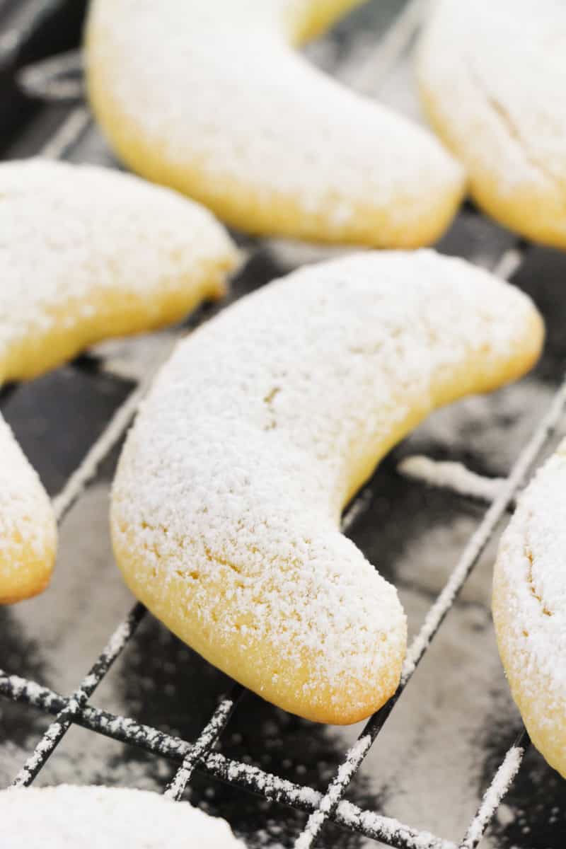 close up italian almond crescent cookies on cooling rack after being dusted with sugar