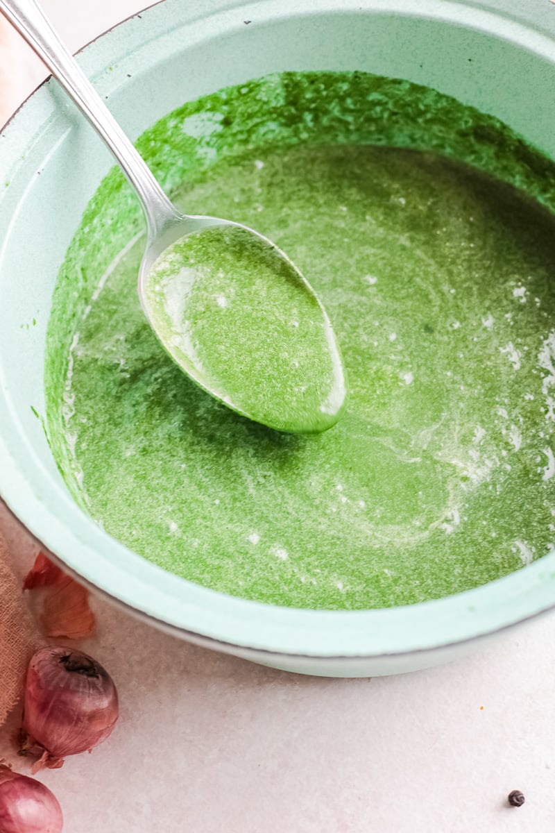 large gray bowl of green vegan spinach soup with spoon