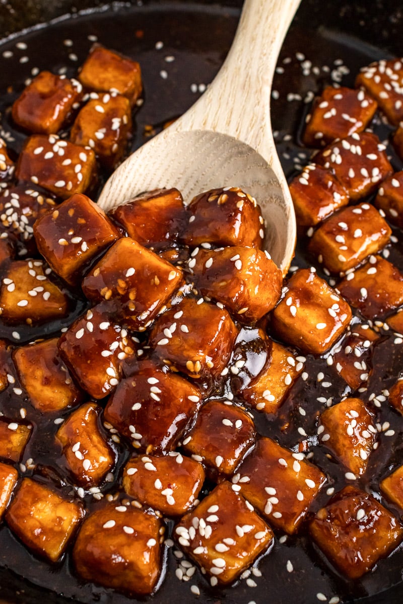 stirring the general tso tofu with a wooden spoon