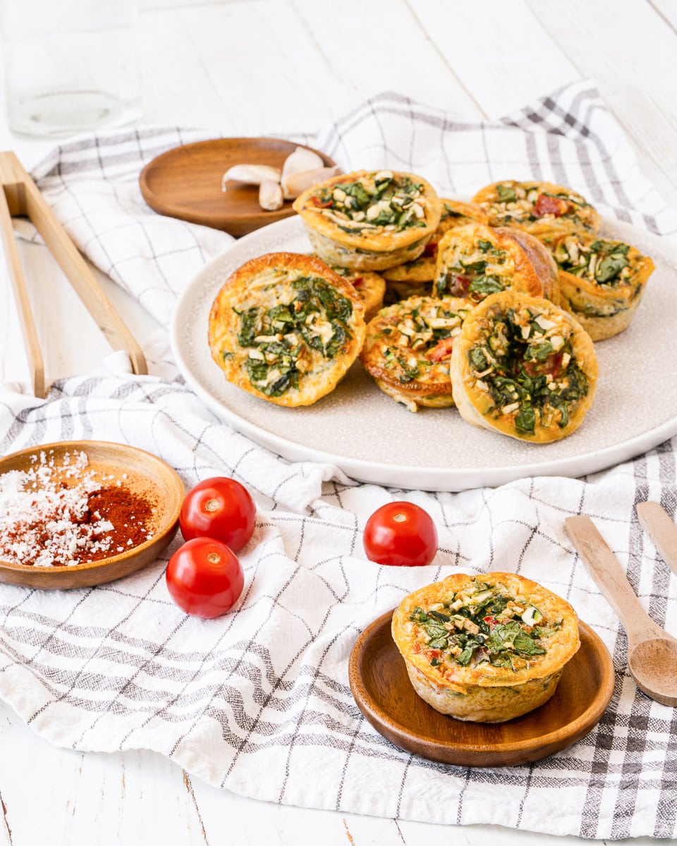 large plate of muffin tin egg bites next to small plate with one muffin