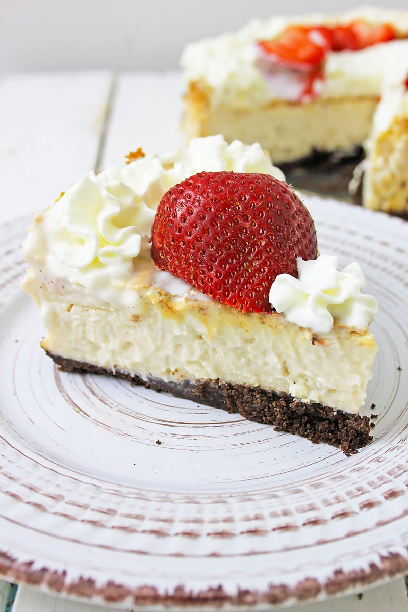 side view slice of the best vegan cheesecake with large strawberry on top