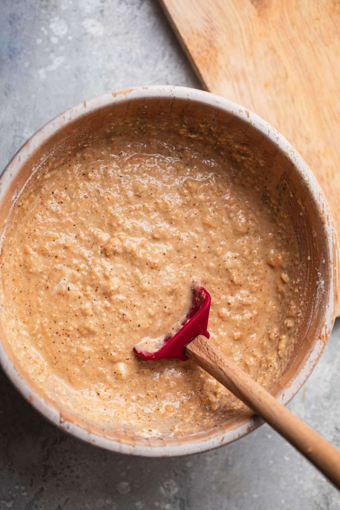 Thick pumpkin pancake batter in a mixing bowl with a red spatula