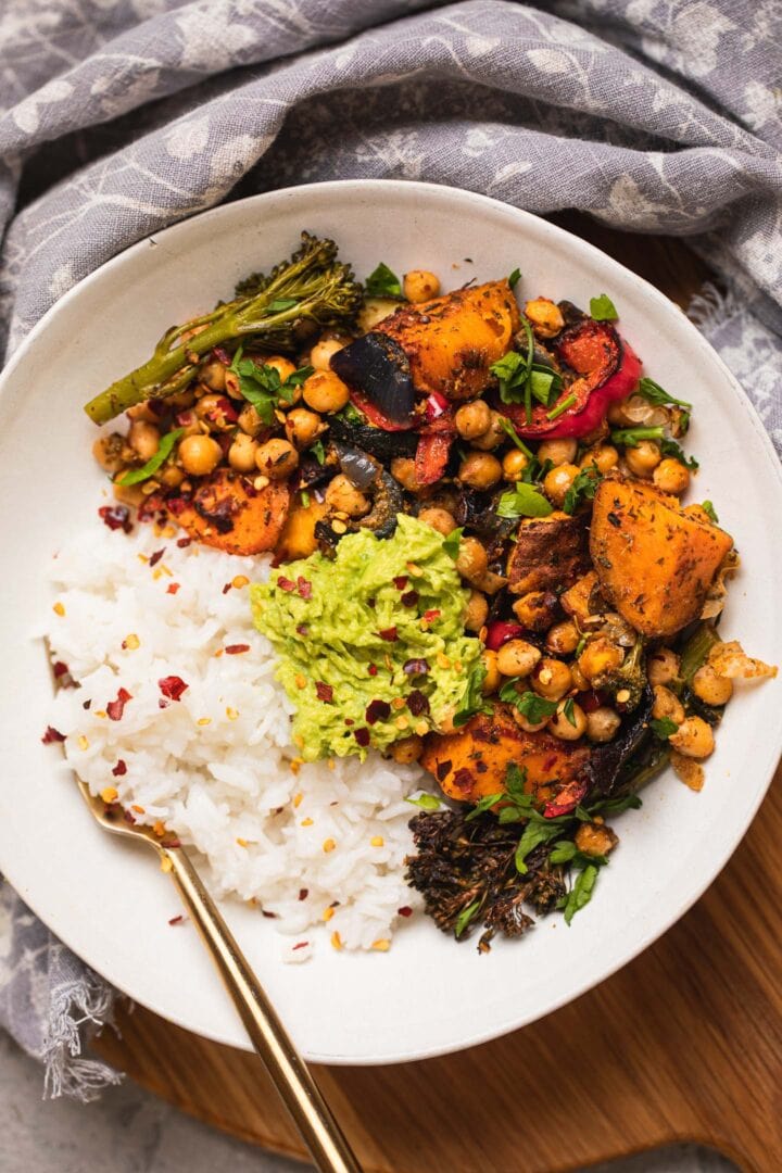 Bowl of roasted vegetables and chickpeas with rice and avocado