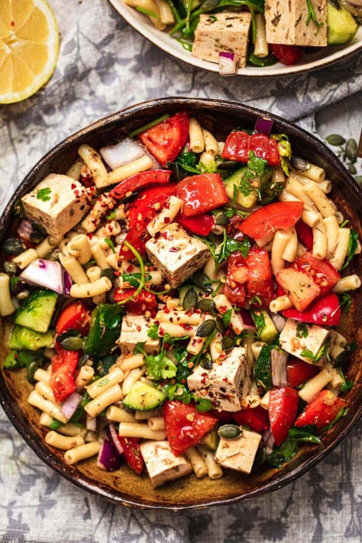 Bowl of vegan pasta salad with tofu feta and vegetables
