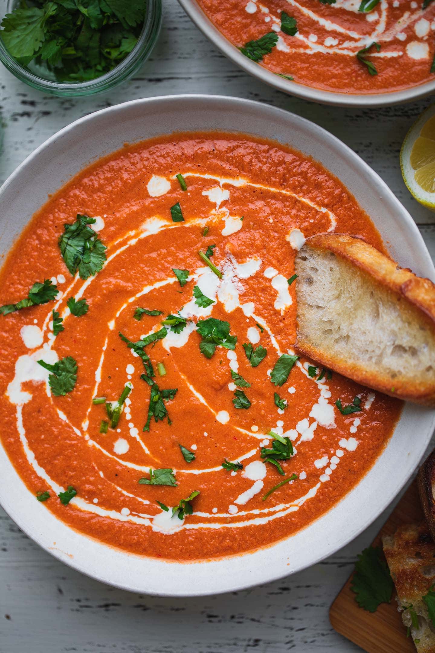 Bowl of vegan tomato soup with bread and coriander