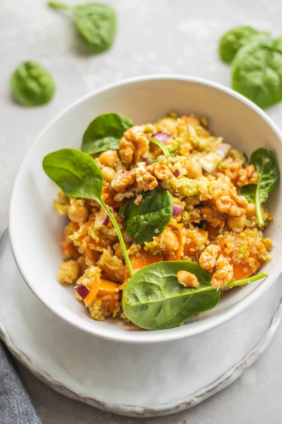Pumpkin quinoa bowl topped with walnuts and baby spinach leaves