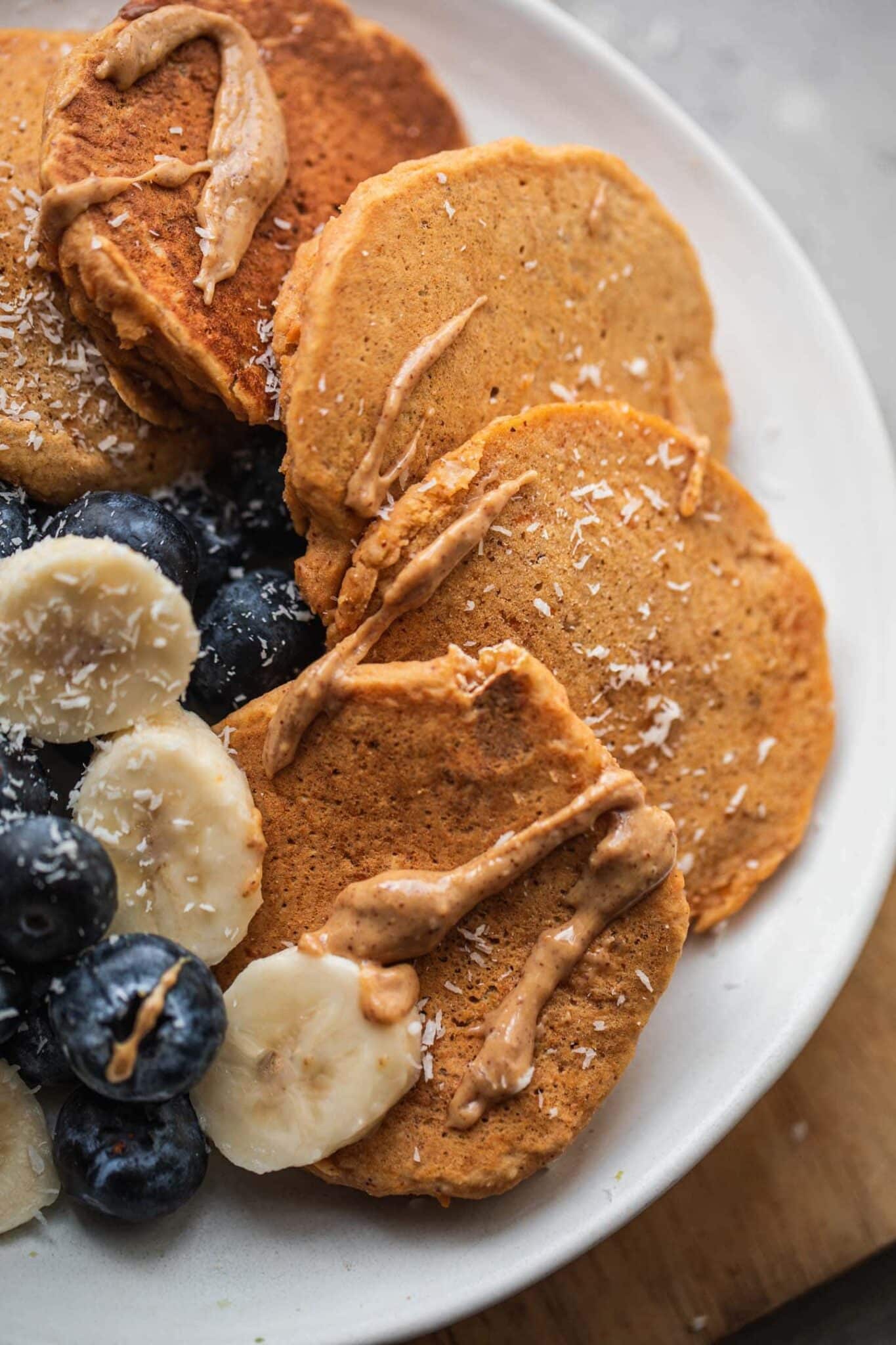 Close-up of fluffy pumpkin pancakes with berries and sliced banana