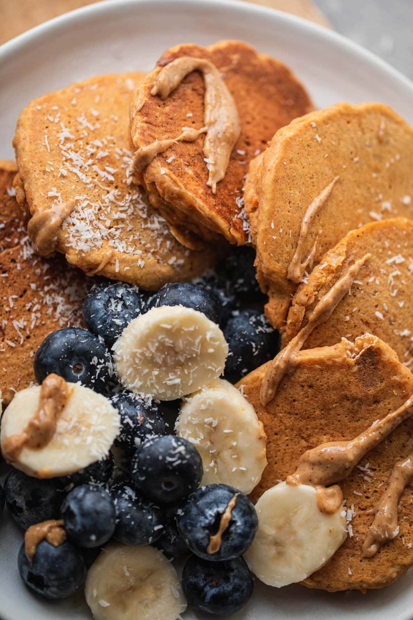 Close-up of vegan pumpkin pancakes with blueberries, banana and almond butter